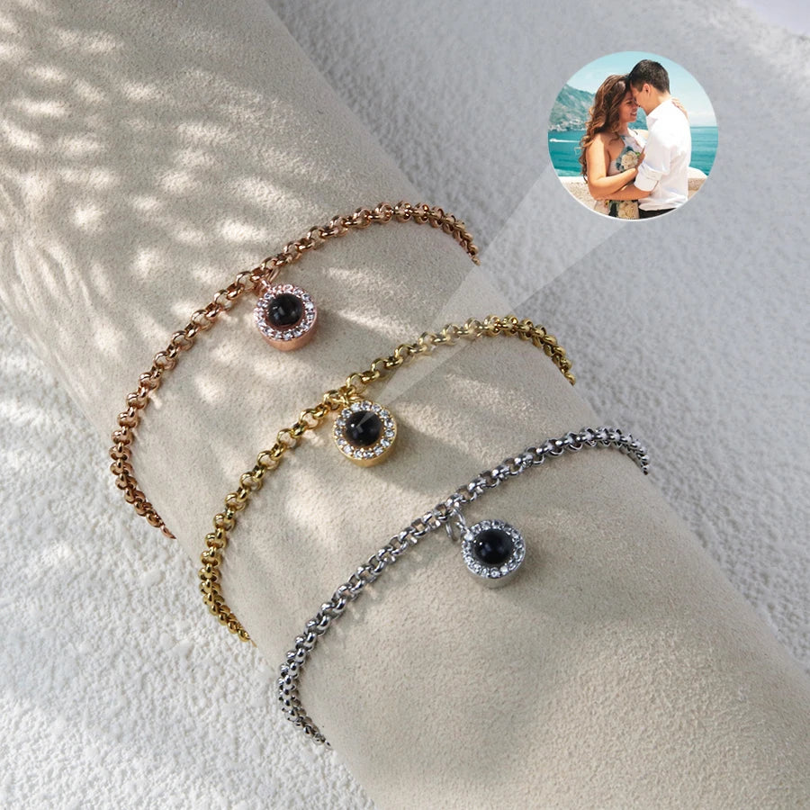 Rose gold, gold and silver tone halo charm photo bracelets on a roll, one projecting a beach couple