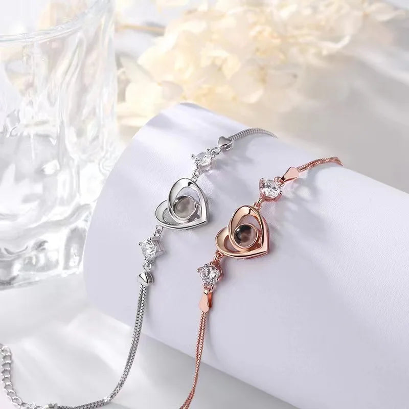 Silver and rose gold heart projection bracelets side by side on a white cylinder display