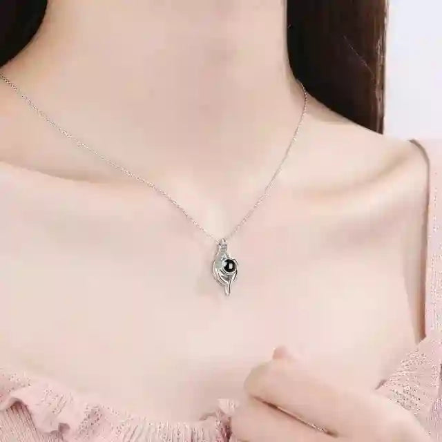 Woman in a pink top wearing a silver photo projection necklace with a drop-shaped pendant