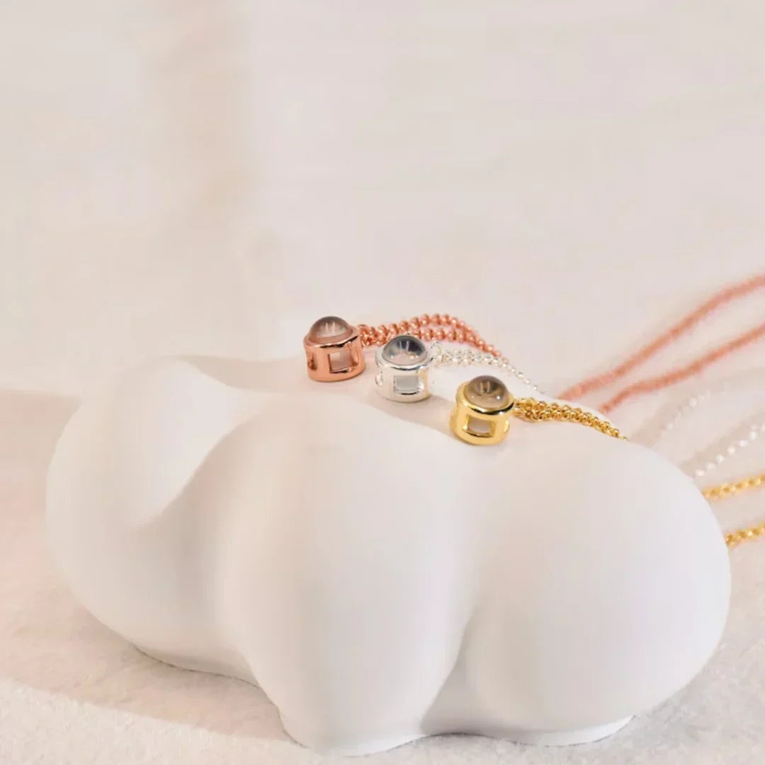 Rose gold, silver and gold round photo pendants side by side on a white cloud-shaped jewelry stand