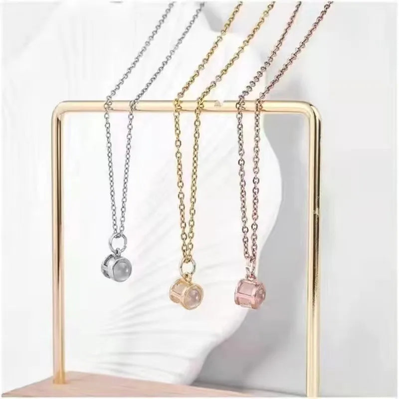 Silver, gold and rose gold photo necklaces with small round pendants hanging from a gold jewelry stand